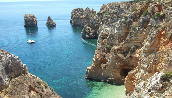 Viajar para Portugal é muito mais do que um destino turístico; é uma viagem ao coração da cultura, história e beleza natural. Ao pisar em solo português, você se vê imerso em uma terra onde o passado e o presente se entrelaçam de forma harmoniosa. Das ruas de pedra de Lisboa, onde o fado ecoa em cada esquina, às praias deslumbrantes da Nazaré, onde as ondas gigantes desafiam surfistas do mundo todo, Portugal oferece uma experiência única para cada tipo de viajante.

Cada cidade portuguesa conta uma história. Em Porto, o aroma do vinho homônimo que envelhece nas caves ao longo do Rio Douro convida você a uma degustação que transcende o paladar, revelando séculos de tradição. Em Sintra, os palácios de contos de fadas e os jardins exuberantes parecem saídos de um sonho, evocando uma época de realeza e mistério. Já no Alentejo, a tranquilidade das planícies douradas convida à introspecção, oferecendo uma pausa revigorante da agitação do dia a dia.

Portugal é também um paraíso para os amantes da gastronomia. Saborear um pastel de nata fresquinho em uma pastelaria de Lisboa, degustar frutos do mar preparados com perfeição em uma taverna à beira-mar no Algarve, ou brindar com um vinho verde em uma adega familiar são experiências que vão muito além de uma simples refeição. É uma conexão com as raízes de um povo que valoriza o sabor e a qualidade em cada prato.

Mas o verdadeiro encanto de Portugal está nas pessoas. A hospitalidade calorosa dos portugueses faz com que você se sinta em casa, seja em uma pequena vila rural ou em um animado bairro urbano. Eles compartilham com orgulho suas tradições, histórias e segredos locais, garantindo que sua viagem seja enriquecida com momentos autênticos e inesquecíveis.

Viajar para Portugal não é apenas visitar monumentos ou paisagens deslumbrantes; é uma jornada que toca a alma, onde cada experiência é uma oportunidade de se conectar com algo mais profundo. É um país que encanta, inspira e deixa uma marca duradoura em todos que o exploram. Ao partir, você não estará simplesmente indo embora; estará levando consigo um pedaço de Portugal no coração.